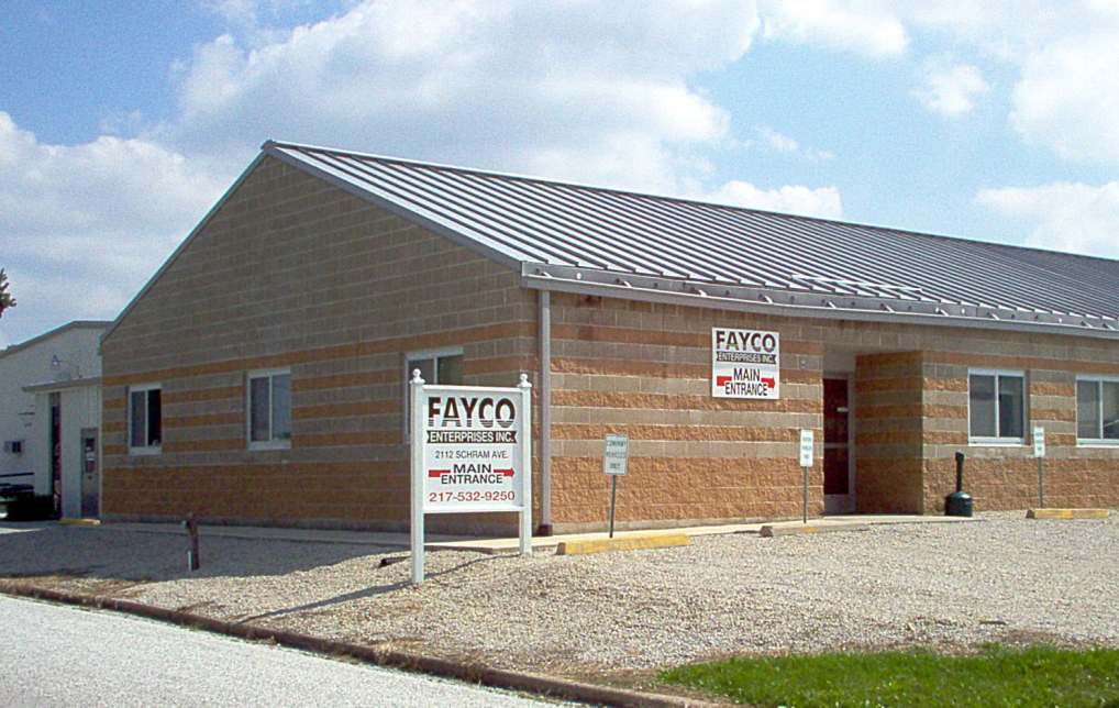 brick and stone building exterior with metal pitched roof, gravel parking lot and entrance sign