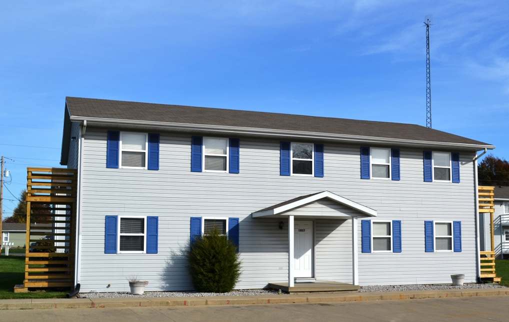 Two story housing complex, blue vinyl siding and bright blue shutters on nine windows